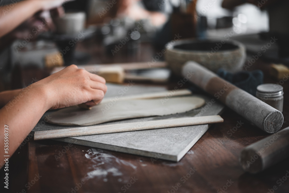 View of female hands works with clay makes future ceramic plate, ceramic artist makes classes of hand building in modern pottery workshop, creative people handcrafted design View of female hands works with clay makes future ceramic plate, ceramic artist makes classes of hand building in modern pottery workshop, creative people handcrafted design