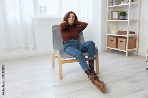 Upset frustrated thoughtful curly adorable woman hold hands behind head lost in sad thoughts about irreparable mistake decision about divorce sit in chair at home looks aside. Heavy thoughts concept