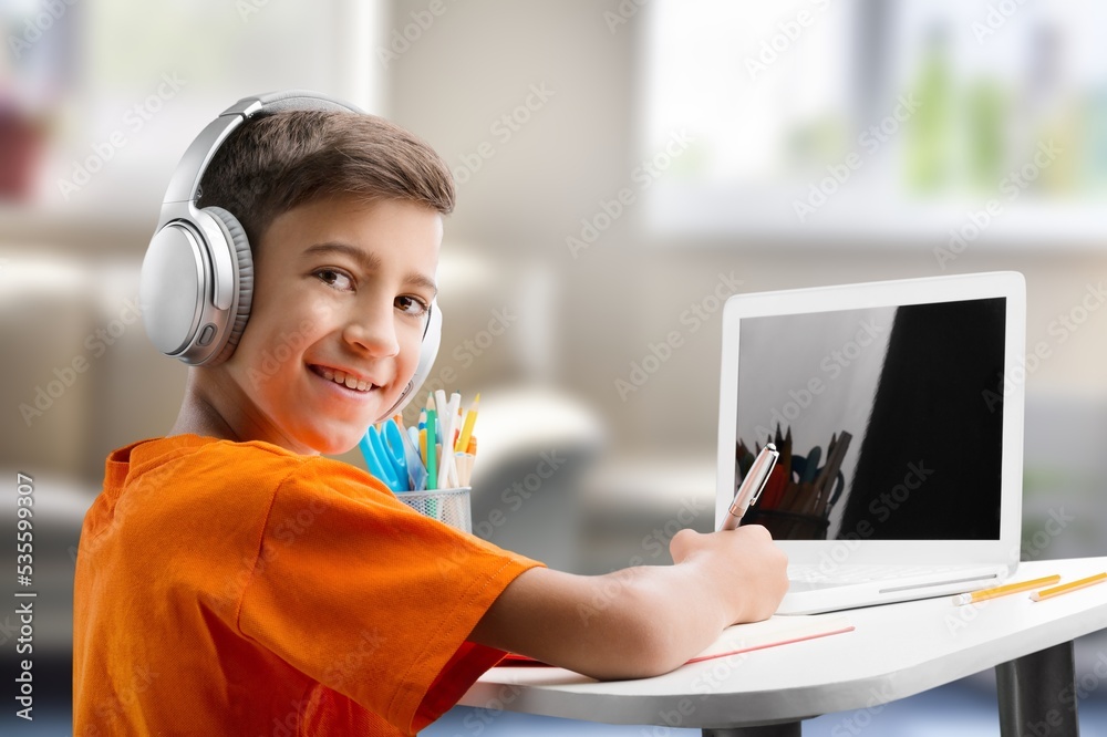 Child in headphones studding on a computer at room Child in headphones studding on a computer at room