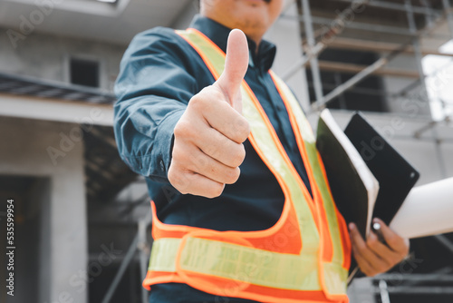 A professional home builder inspects the house structure and gives a thumbs up to show his satisfaction in the job,