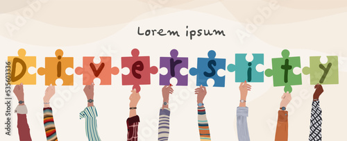 Hands raised up group of diverse and multicultural people holding puzzle pieces with letters forming the word -Diversity-. Racial equality concept. Variety of people. Banner copy space