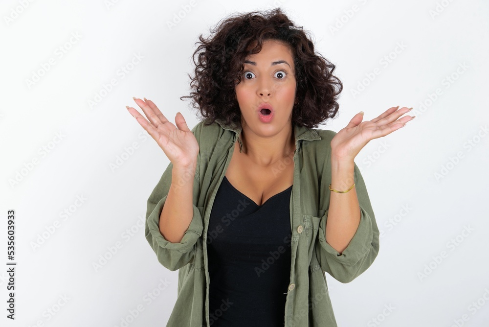 Surprised terrified young beautiful woman with curly short hair Gestures with uncertainty, stares at camera, puzzled as doesn't know answer on tricky question, People, body language, emotions concept Surprised terrified young beautiful woman with curly short hair Gestures with uncertainty, stares at camera, puzzled as doesn't know answer on tricky question, People, body language, emotions concept