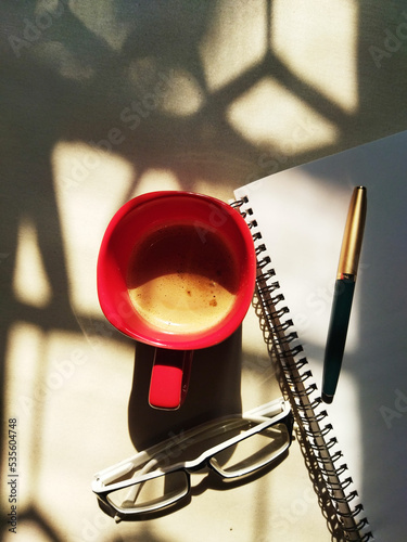 cup of coffee and notebook. Red coffee cup,pen,glass,paper