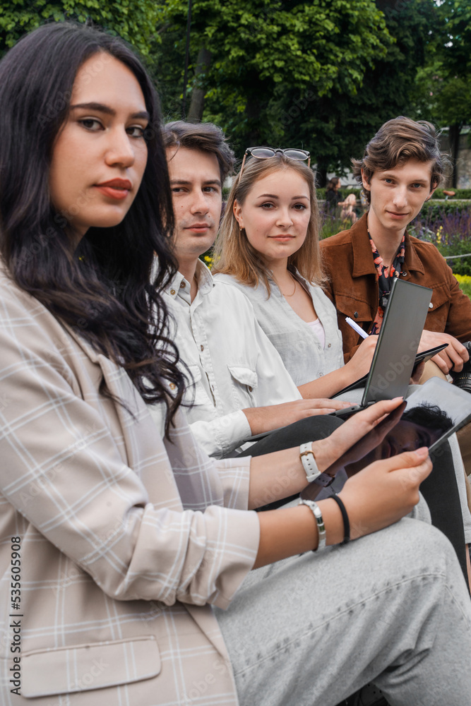 Shot of students sitting on bench near fountain browsing laptop and tablet. Shot of students sitting on bench near fountain browsing laptop and tablet.