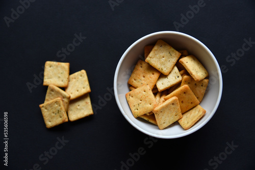 Photo Delicious peppery cookies in a white plate on a black background.