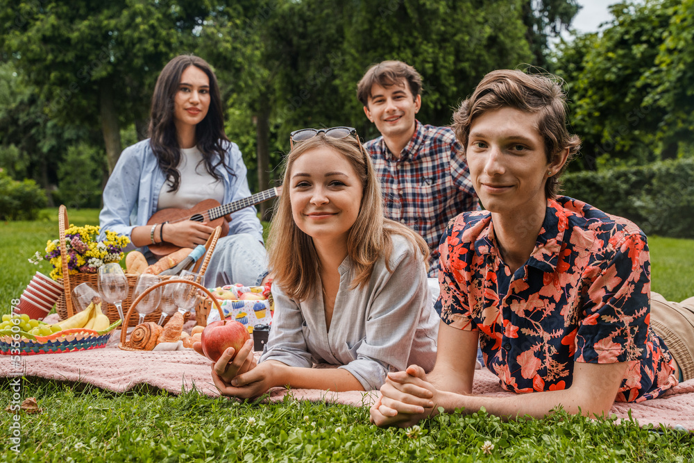 Fototapeta premium Portrait of four young friend having time together at picnic with some food and drink.