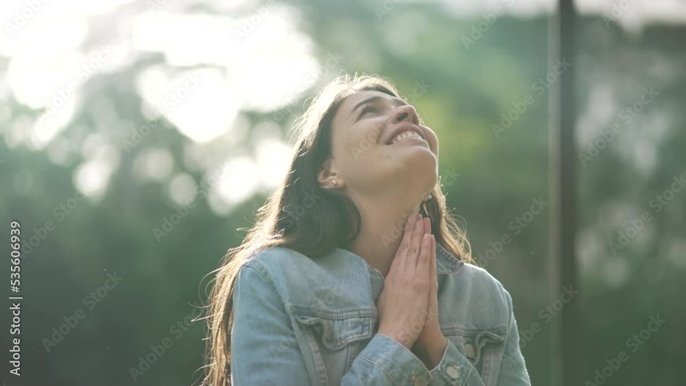 Grateful spiritual young woman thanking God praying to sky smiling. Happy free person looking at sky with HOPE and FAITH