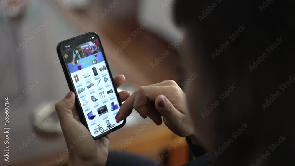 Hands holding smartphone device browsing website searching for household items to buy on online store