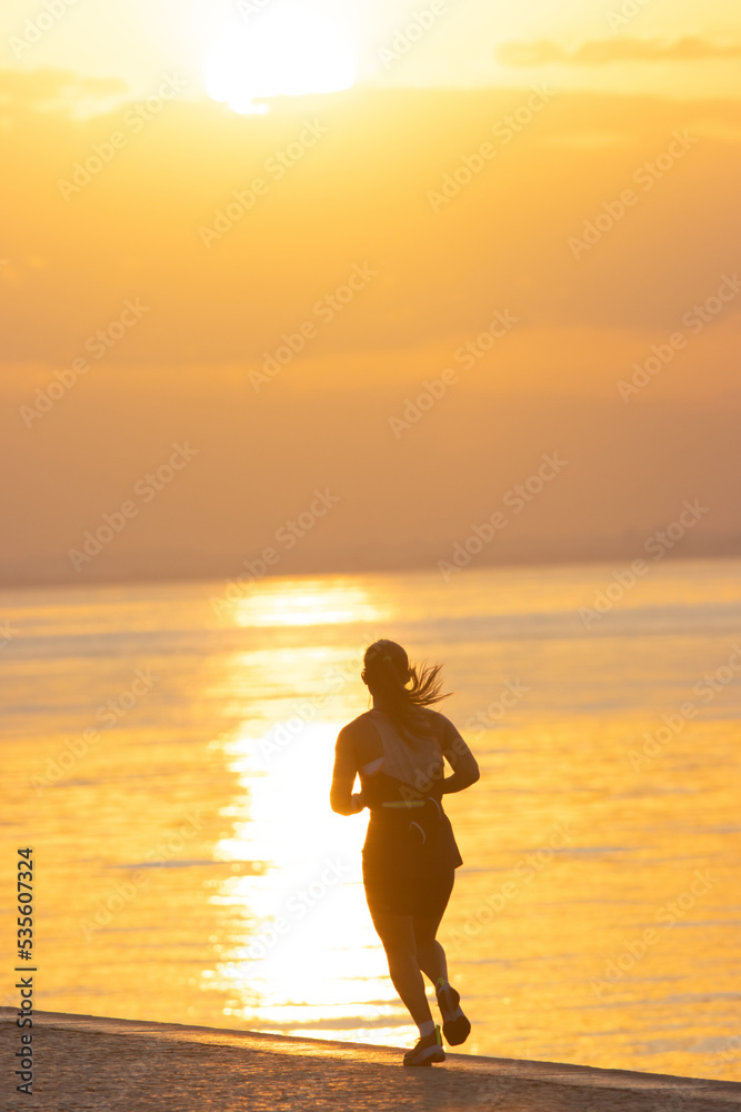 Silhouette of young athletic woman are running on the river