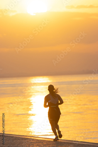 Fototapeta Naklejka Na Ścianę i Meble -  Silhouette of young athletic woman are running on the river