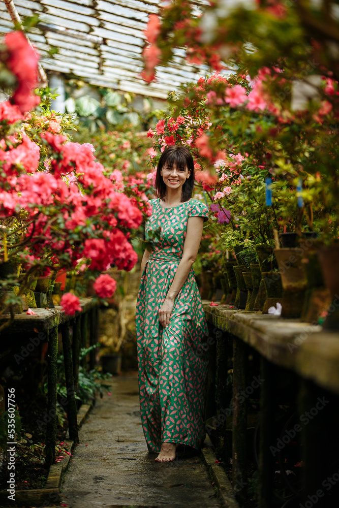 A girl in a green dress among a blooming garden of azaleas