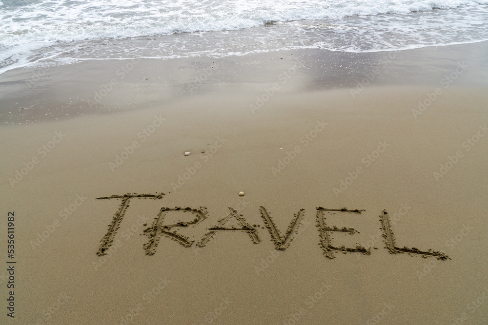 Fototapeta premium Words Written in the sand. The word TRAVEL written in the sand with the ocean in the background.