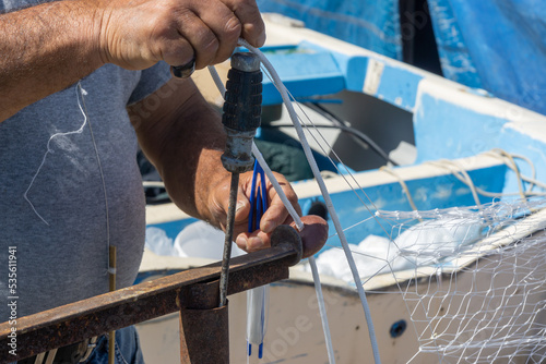 a fisherman is working at fishing nets in the harbor of Anzio, Rome, Italy