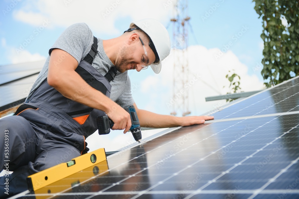 Male engineer in protective helmet installing solar photovoltaic panel system. Alternative energy ecological concept. Male engineer in protective helmet installing solar photovoltaic panel system. Alternative energy ecological concept.