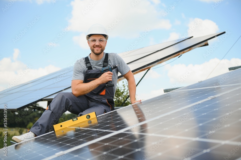 Worker installing solar panels outdoors Worker installing solar panels outdoors