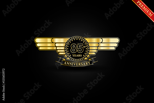85th anniversary golden wing gold logo with gold ring and ribbon isolated on black background, vector design for celebration. photo