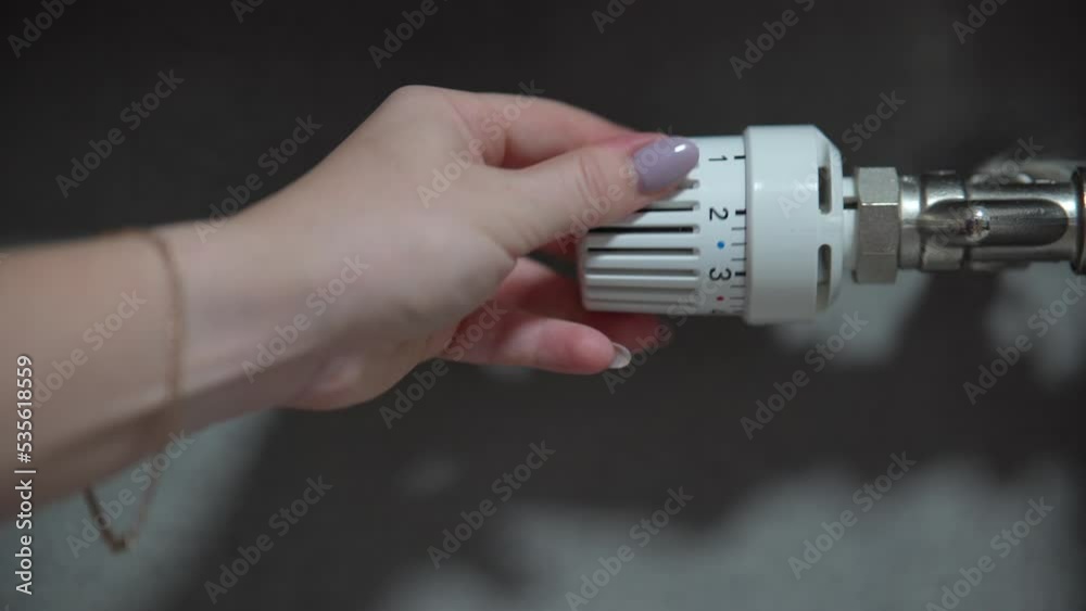 Hand adjusting temperature on heating radiator thermostat, saving energy by adjusting heating thermostat. Hand adjusting temperature on heating radiator thermostat, saving energy by adjusting heating thermostat.