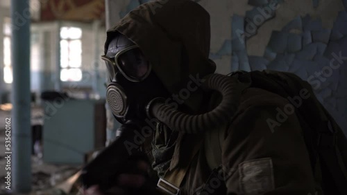 Stalker in a gas mask with a gun in an abandoned factory building. Soldier aims with a pistol