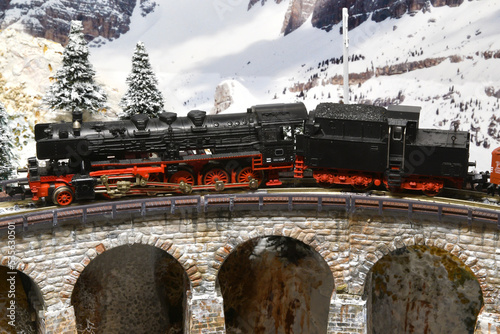 model of a steam train locomotive on a viaduct in winter mountain ambientation photo