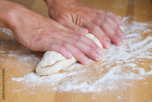 Hands of man crumples and kneading dough while making bread in the kitchen