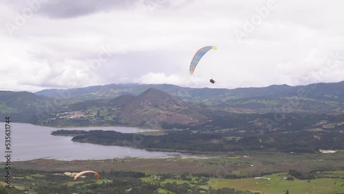 three paraglides fly near a reservoir photo