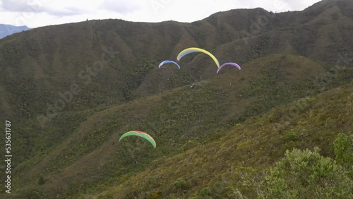 four paraglides fly near a mountain range photo