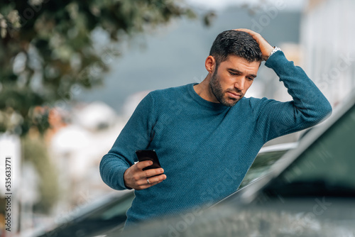 man with mobile phone in dealership looking at cars to buy with surprised expression