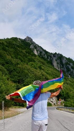 Bisexual, gay, old man, male, transgender walk back with LGBTQIA flag, rainbow peace in pride mounts on the nature on a day and celebrate Bisexuality Day or National Coming Out Day