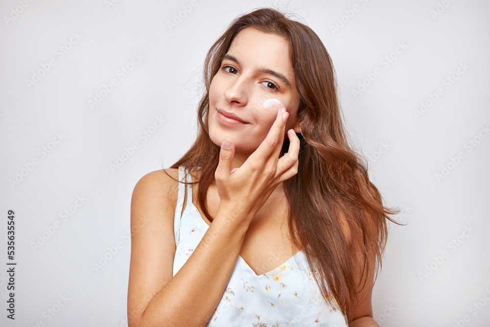 A beautiful girl applies moisturizing cream to her face. A beautiful girl applies moisturizing cream to her face.