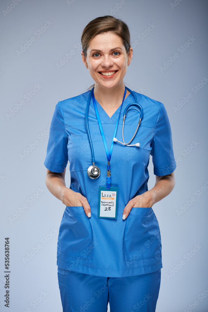 Smiling nurse woman with hands in pockets. Isolated female portrait.