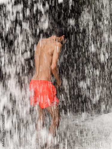 Man standing under a waterfall photo