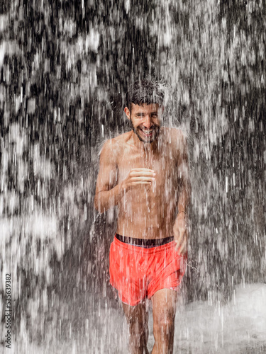 Man standing under a waterfall photo