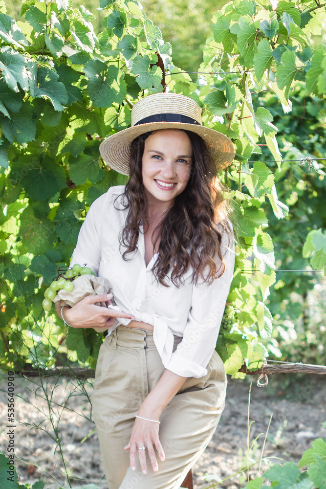 A young girl on a grape plantation holds bunches of grapes in her hand