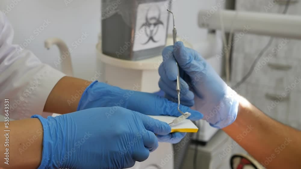 The dental assistant gives the dentist the prepared solution for filling the tooth to the patient in the process. Placement of a filling in a tooth according to the color of the tooth The dental assistant gives the dentist the prepared solution for filling the tooth to the patient in the process. Placement of a filling in a tooth according to the color of the tooth