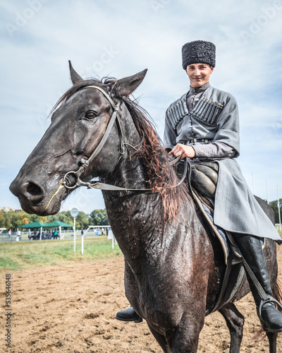 A young Cossack rider in a national Caucasian costume is sitting horseback posing