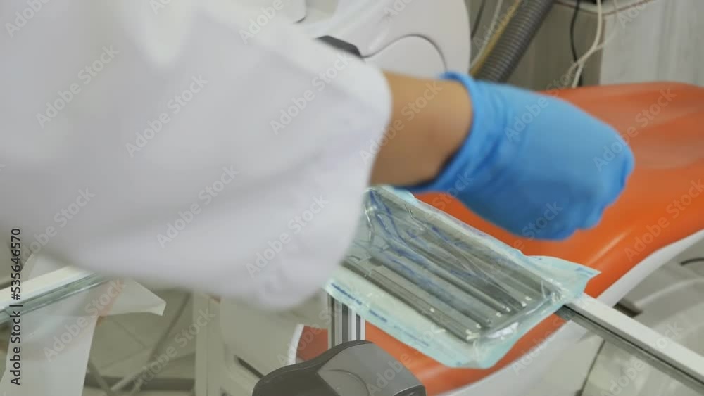 The hands of a dental assistant in blue gloves placed a set of dental ...