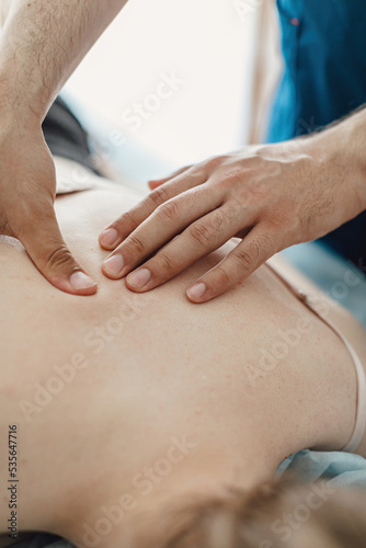 Men's hands make a therapeutic neck massage for a girl lying on a massage couch.