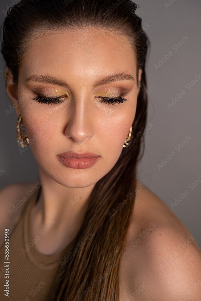 Closeup fashionable, elegant woman face with professional make up, golden accessories in ears. Wedding gifts for women Closeup fashionable, elegant woman face with professional make up, golden accessories in ears. Wedding gifts for women
