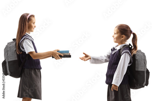 Older girl giving books to a younger schoolgirl