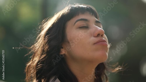 Woman with eyes closed in meditation standing outside in sunlight. Contemplative person feeling tranquility and relaxation photo