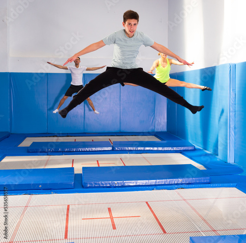 Portrait of teenager boy training jumping movements during workout in indoor trampolines center