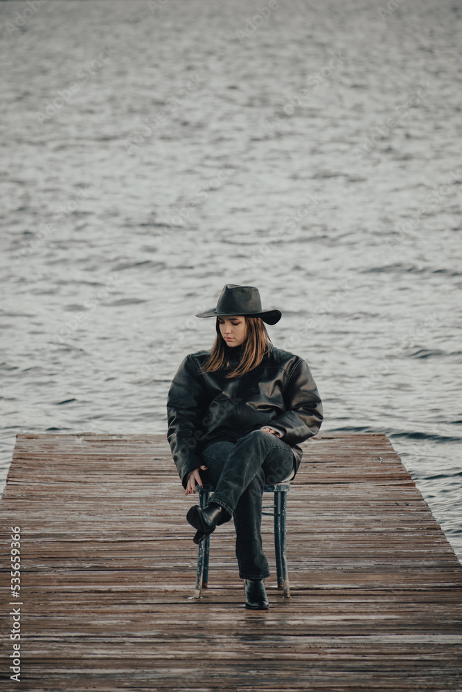 cowboy girl sitting in the saddle on the snow with a hat and leather jacket on a cloudy day