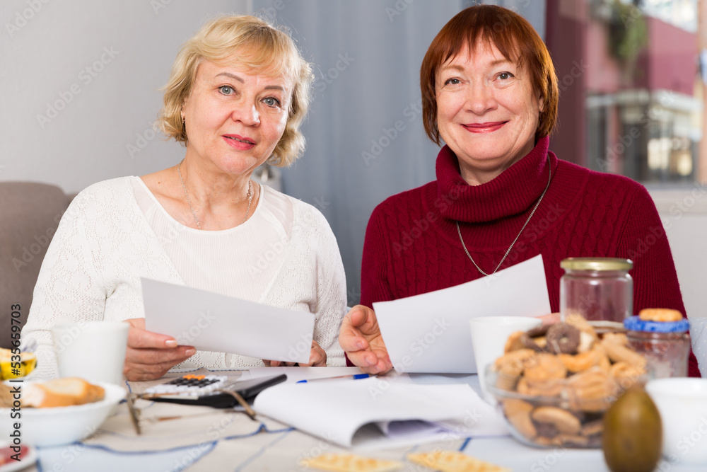 Portrait of cheerful mature females with documents communal payments
