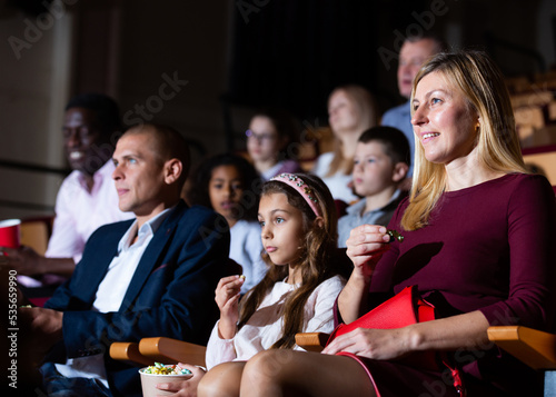 caucasian family sitting at funny premiere in cinema