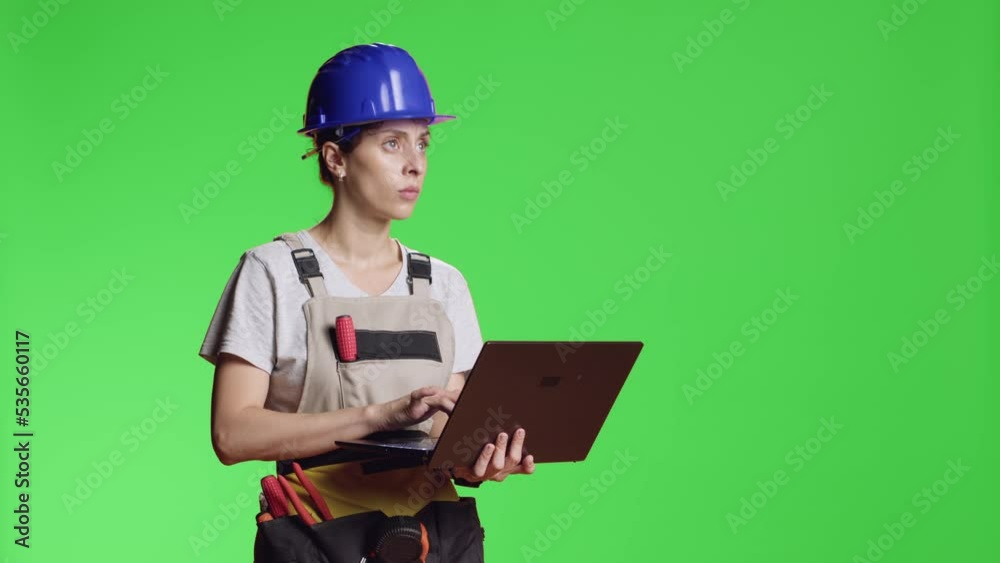 Female construction worker browsing internet on laptop to find refurbishment inspiration, standing over greenscreen isolated background. Woman using pc over chroma key template. Female construction worker browsing internet on laptop to find refurbishment inspiration, standing over greenscreen isolated background. Woman using pc over chroma key template.