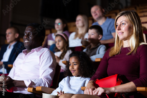 International family enjoys watching comedy in a cinema hall