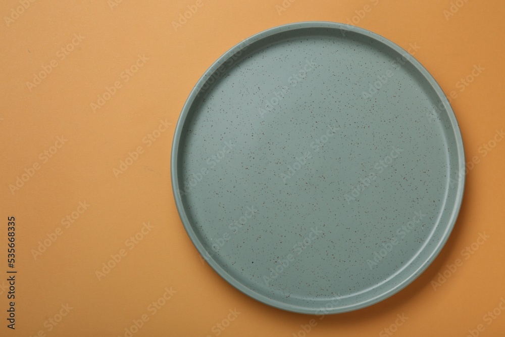Empty ceramic plate on pale orange background, top view. Space for text Empty ceramic plate on pale orange background, top view. Space for text