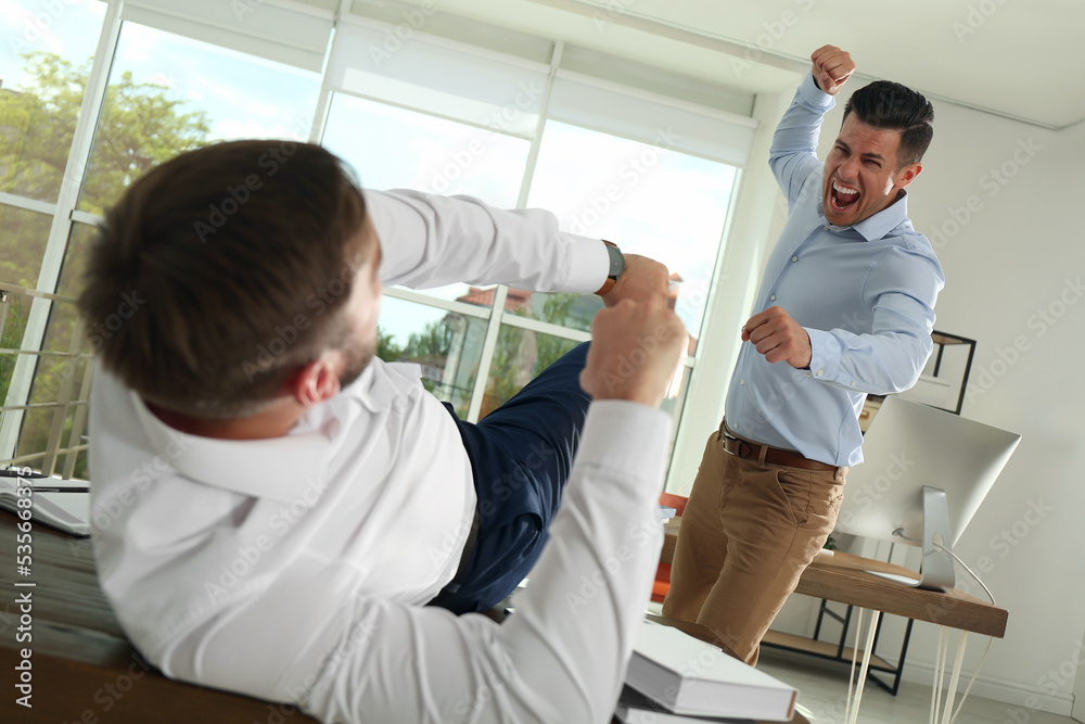 Obraz premium Emotional colleagues fighting in office. Workplace conflict