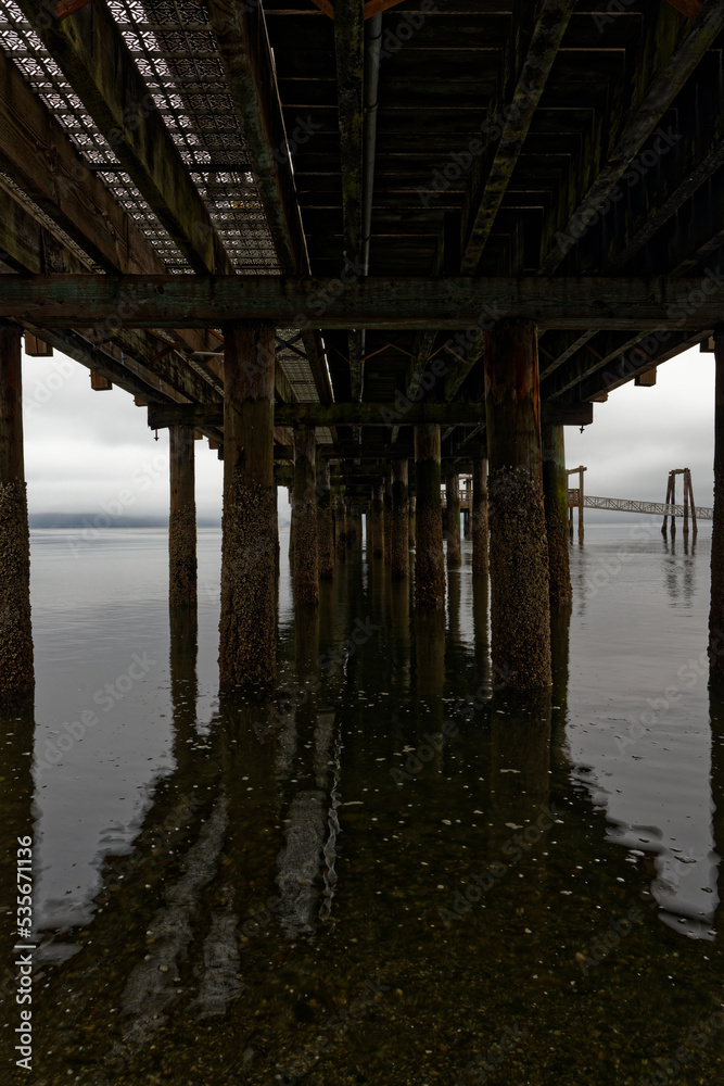Silhouette of wood pilings supporting the Old Town Dock in Tacoma, Washington on a cloudy morning.