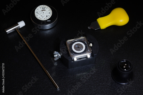 clock machinery which is disassembled on a table and where there is a mini hammer, removes covers and watch cushion.